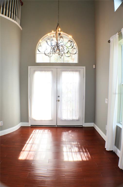 An entryway features hardwood floors, a double door, an arched window, and a chandelier — 11609 GREENSLEEVE AVENUE, TAMPA, FL