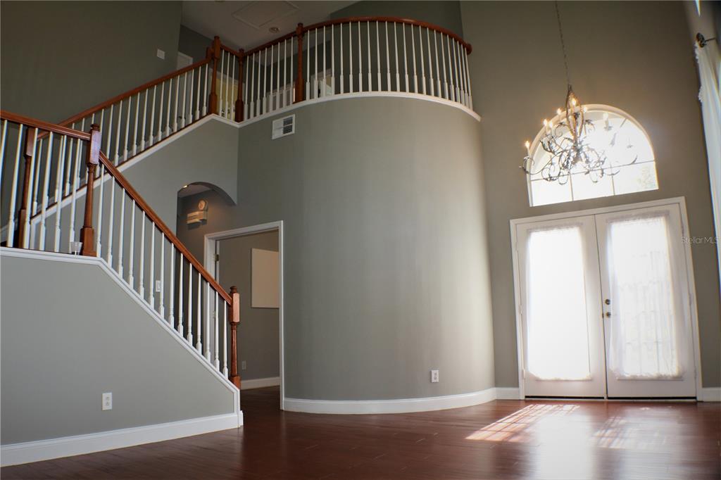 A two-story foyer features a curved staircase, hardwood floors, and a large arched window — 11609 GREENSLEEVE AVENUE, TAMPA, FL