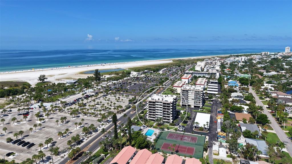 An aerial view shows a multi-story condominium building near a beach and tennis courts — 1055 BEACH ROAD UNIT B602, SARASOTA, FL