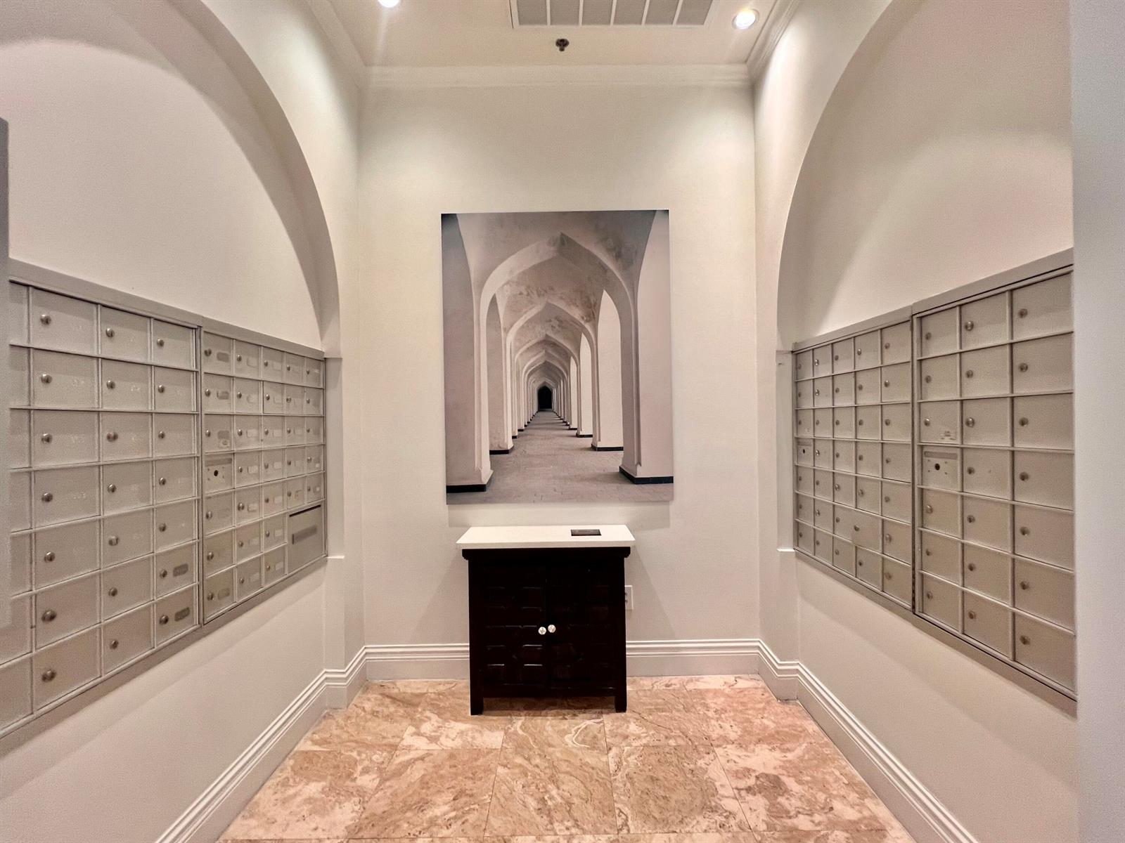 A mailroom features metal mailboxes on both sides, a central cabinet, and a wall art piece — 651 Okeechobee Boulevard # 706, West Palm Beach FL 33401, WEST PALM BEACH, FL
