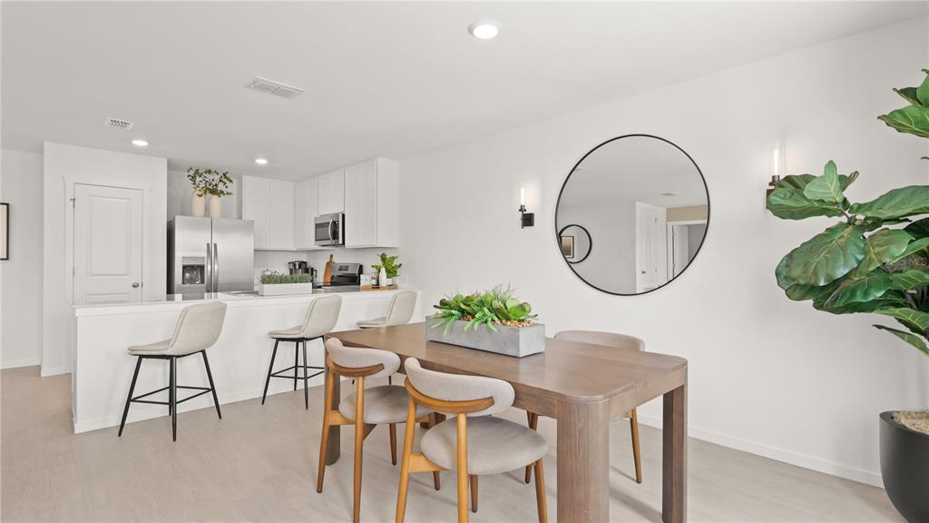 A dining area with a wooden table and chairs sits adjacent to a white kitchen — 311 NOLA LANE, DUNDEE, FL