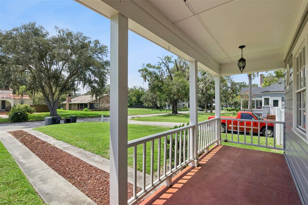 A covered front porch with gray siding, a black door, and a red concrete floor — 207 S SUMMERLIN AVENUE, SANFORD, FL