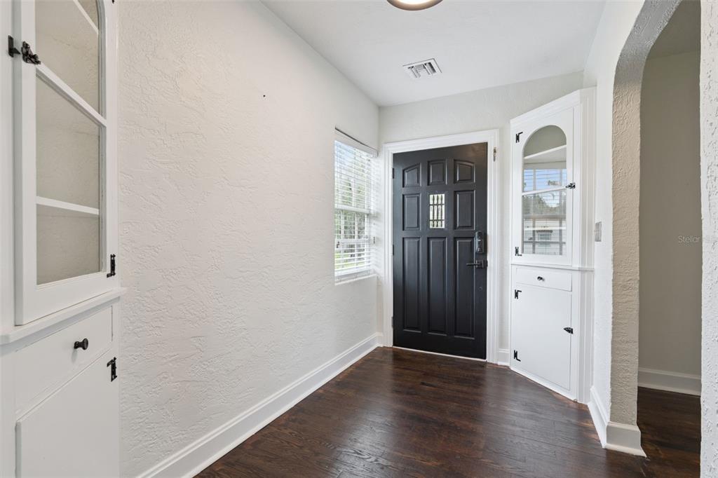 An empty room with dark hardwood floors, white walls, and two arched doorways — 207 S SUMMERLIN AVENUE, SANFORD, FL