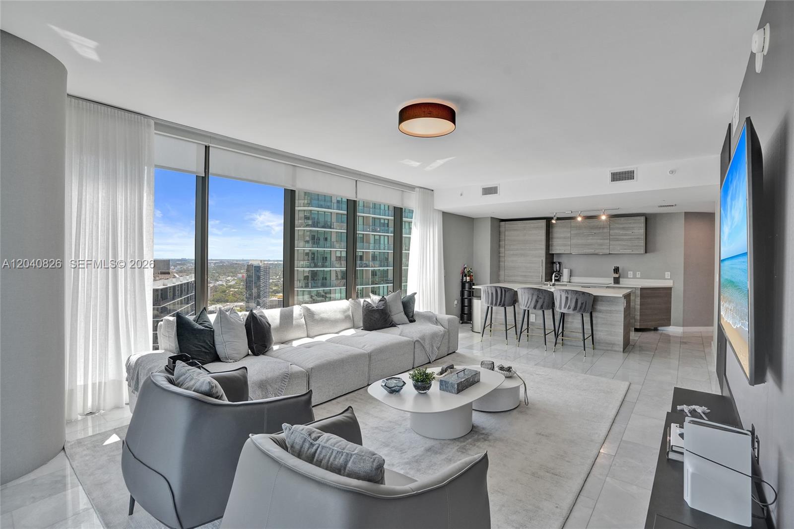 A modern living room features a large sectional sofa, two armchairs, and an open kitchen — 650 NE 32nd St # 3901, Miami FL 33137, MIAMI, FL