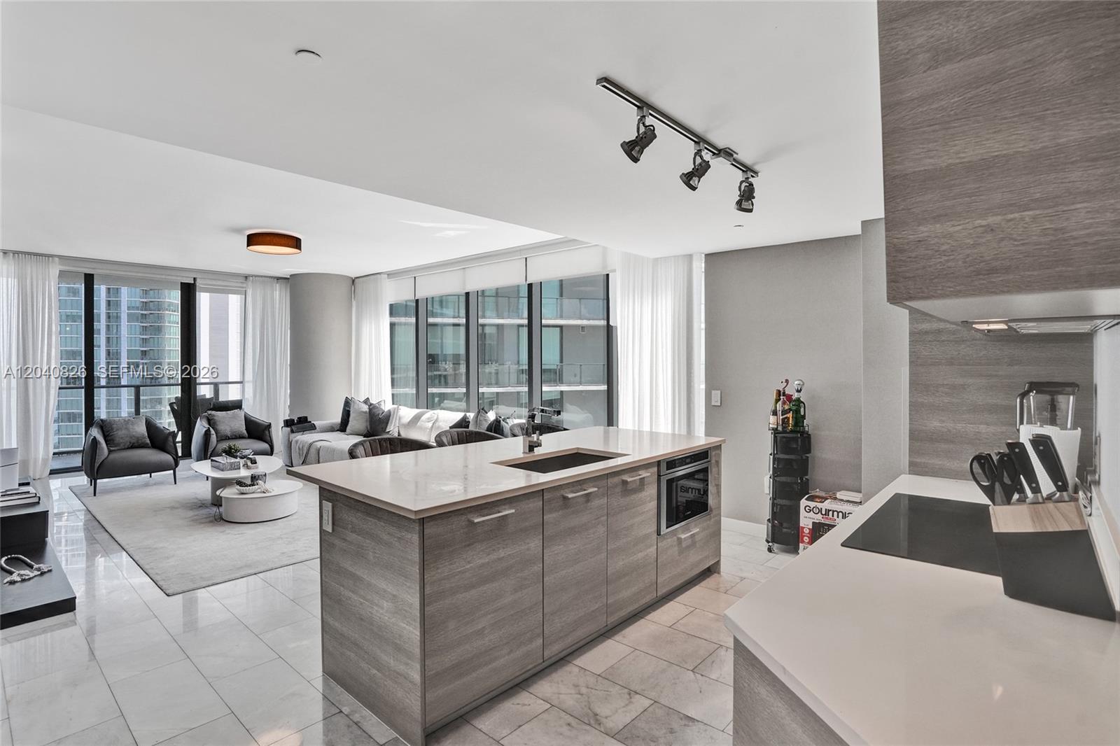 A modern kitchen island with a sink sits in an open-concept living area — 650 NE 32nd St # 3901, Miami FL 33137, MIAMI, FL