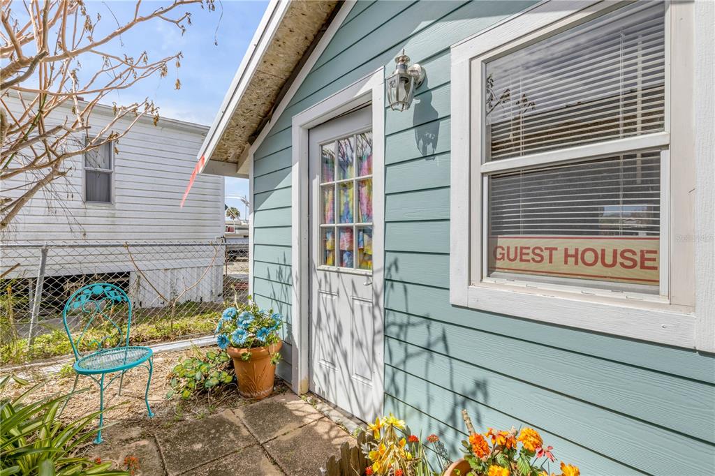 A light blue guest house exterior features a white door, a window, and a patio chair — 201 GARY AVENUE, OAK HILL, FL