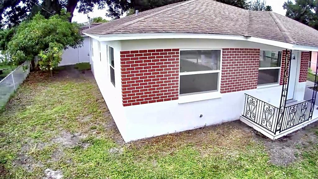 An exterior view of a single-story house with a brick facade, porch, and attached carport — 3117 W LEROY STREET, TAMPA, FL