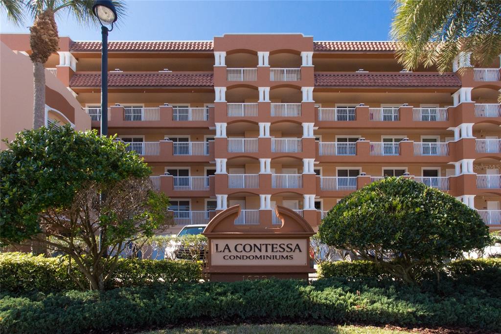A multi-story tan condominium building with white railings and a prominent front entrance sign — 16326 GULF BOULEVARD UNIT 307, REDINGTON BEACH, FL