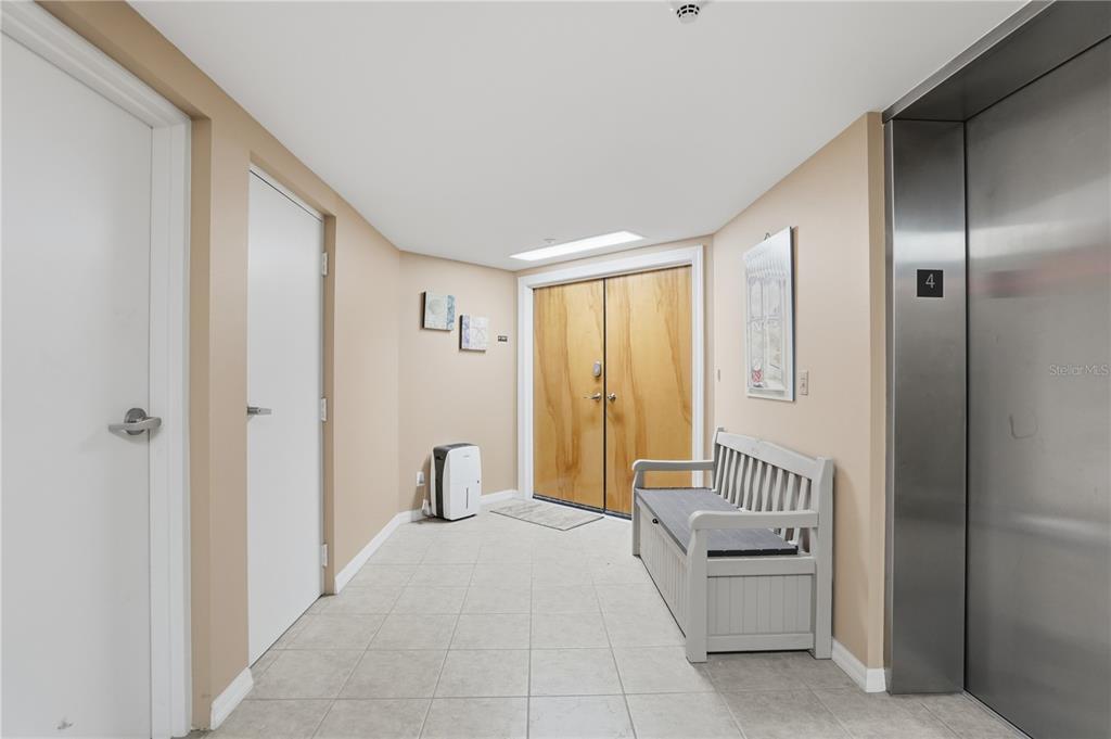 A hallway features tile flooring, a bench, a double wooden door, and an elevator — 16326 GULF BOULEVARD UNIT 307, REDINGTON BEACH, FL