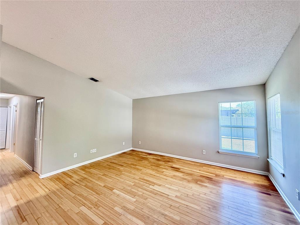 An empty living room features light-colored walls, hardwood flooring, and a textured ceiling — 758 WARRENTON ROAD, WINTER PARK, FL