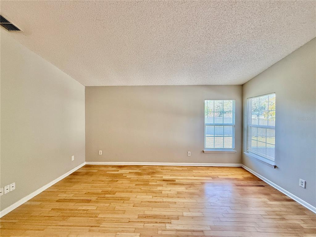 An empty room features light-colored walls, hardwood flooring, and two windows with blinds — 758 WARRENTON ROAD, WINTER PARK, FL