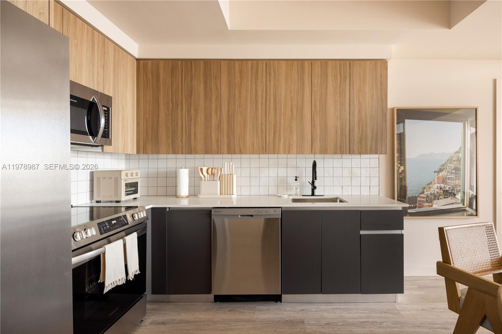 A modern kitchen features wood-toned upper cabinets, dark lower cabinets, and stainless steel appliances — 275 SW 6th St # 2007, Miami FL 33130, MIAMI, FL