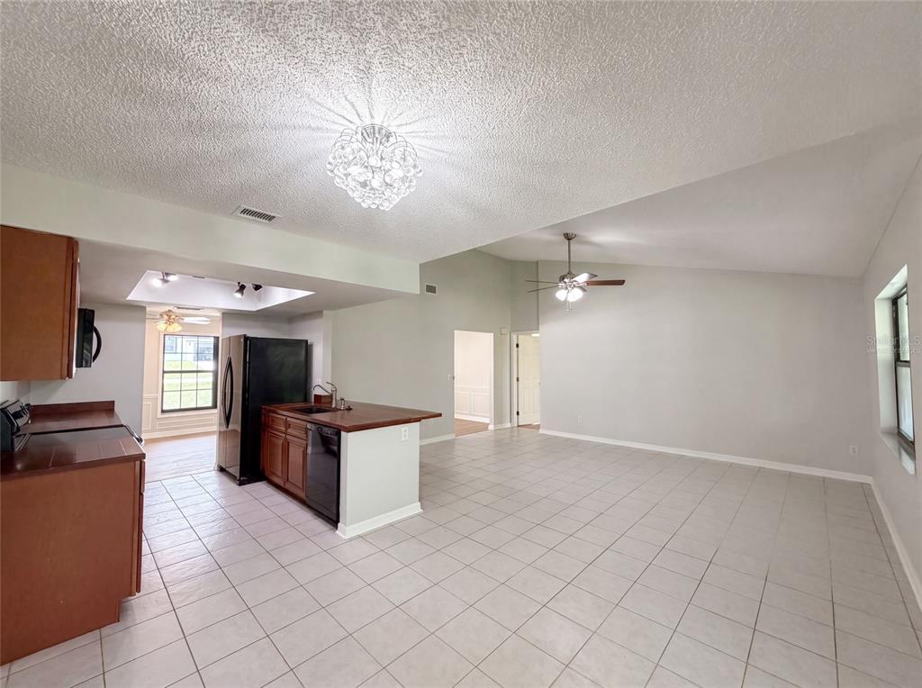 An open-concept kitchen and living area feature tile flooring, dark wood cabinets, and vaulted ceilings — 15226 SW 39TH CIRCLE, OCALA, FL