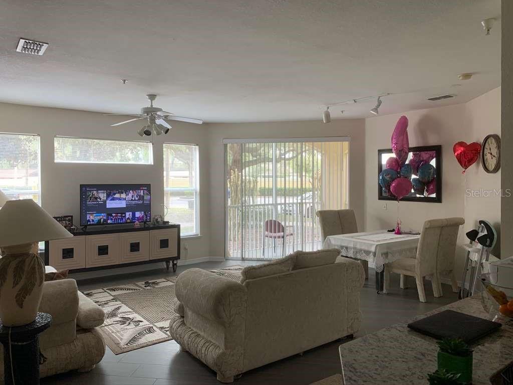 A living room and dining area feature light-colored furniture, a ceiling fan, and sliding doors — 2639 MAITLAND CROSSING WAY UNIT 107, ORLANDO, FL