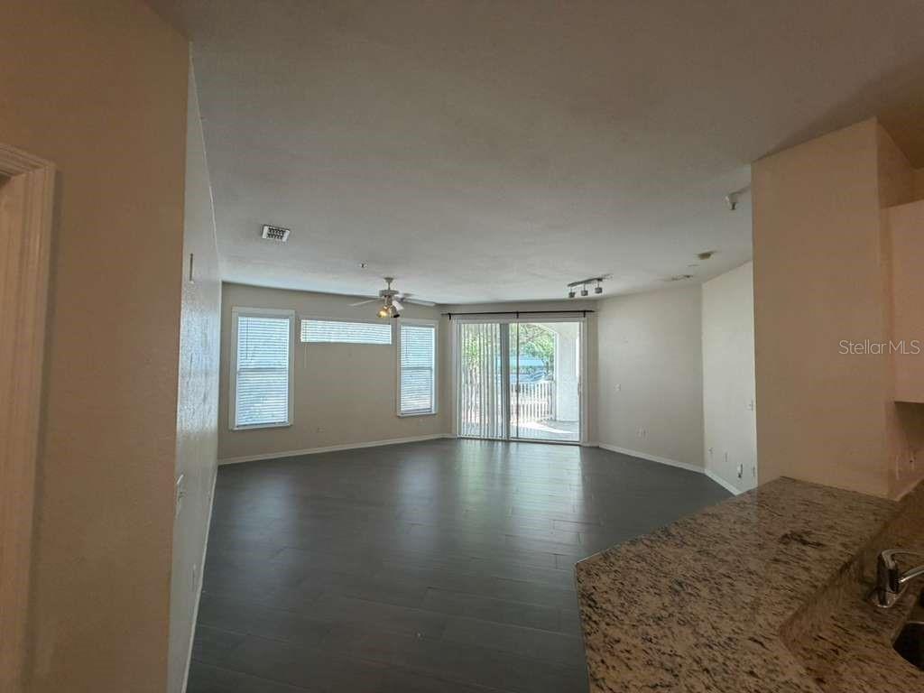 An empty living room with dark wood flooring, a ceiling fan, and sliding glass doors — 2639 MAITLAND CROSSING WAY UNIT 107, ORLANDO, FL