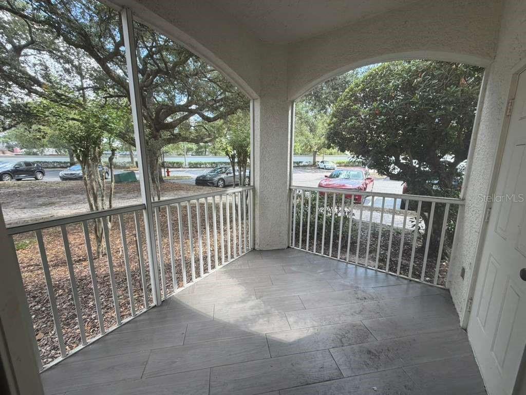 A screened-in porch with light-colored tile flooring and white railings overlooking a parking lot — 2639 MAITLAND CROSSING WAY UNIT 107, ORLANDO, FL
