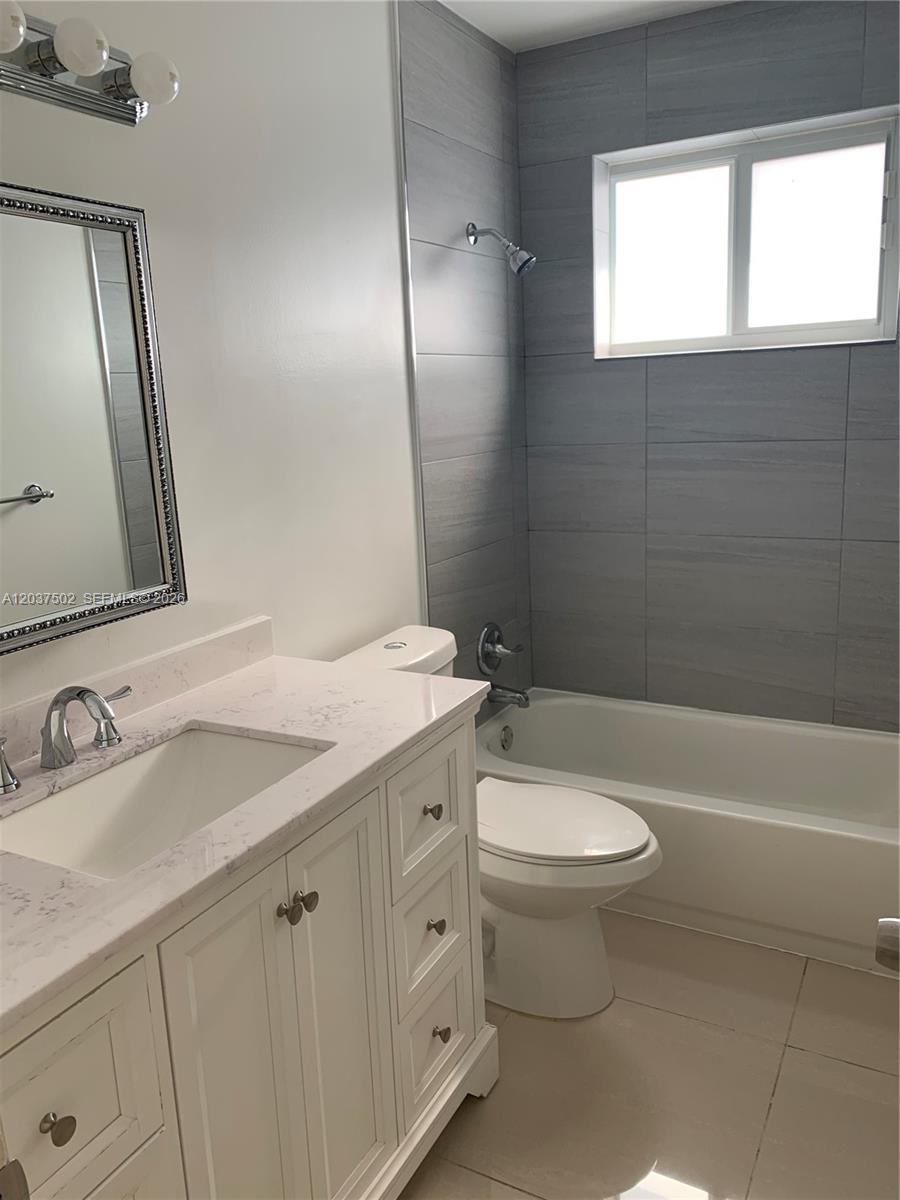 A bathroom features a white vanity, a toilet, and a bathtub with gray tiled walls — 1200 SW 31st Ave, Miami FL 33135, MIAMI, FL