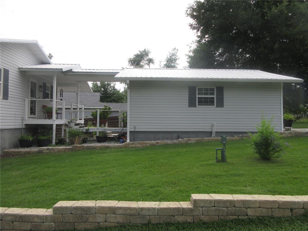 A white-sided house features a covered breezeway connecting to a detached garage with a metal roof — 16849 SE 59TH PLACE, OCKLAWAHA, FL