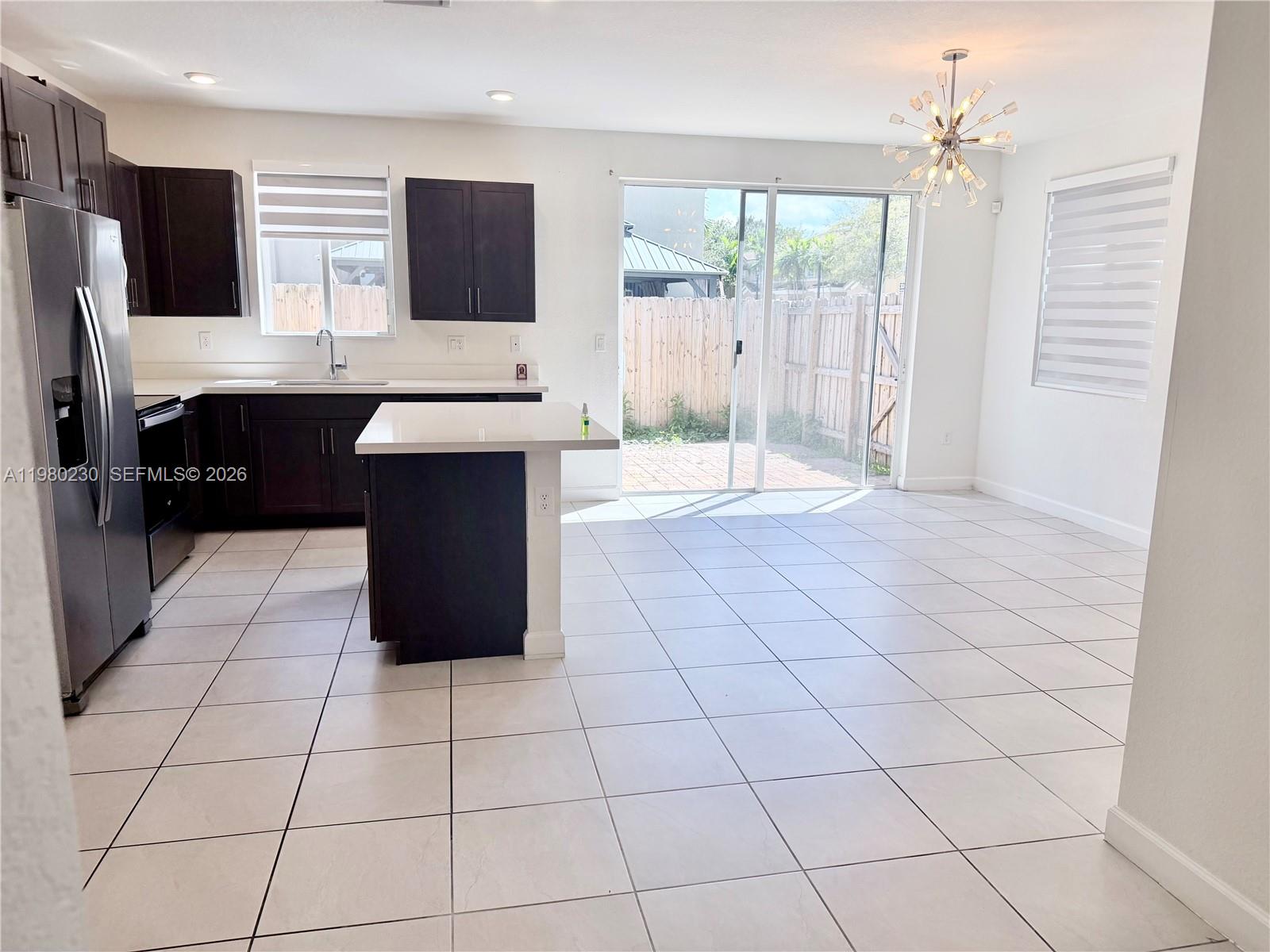 A kitchen features dark cabinetry, a white island, stainless steel appliances, and tile flooring — 2418 SE 10th Ct, Homestead FL 33035, HOMESTEAD, FL