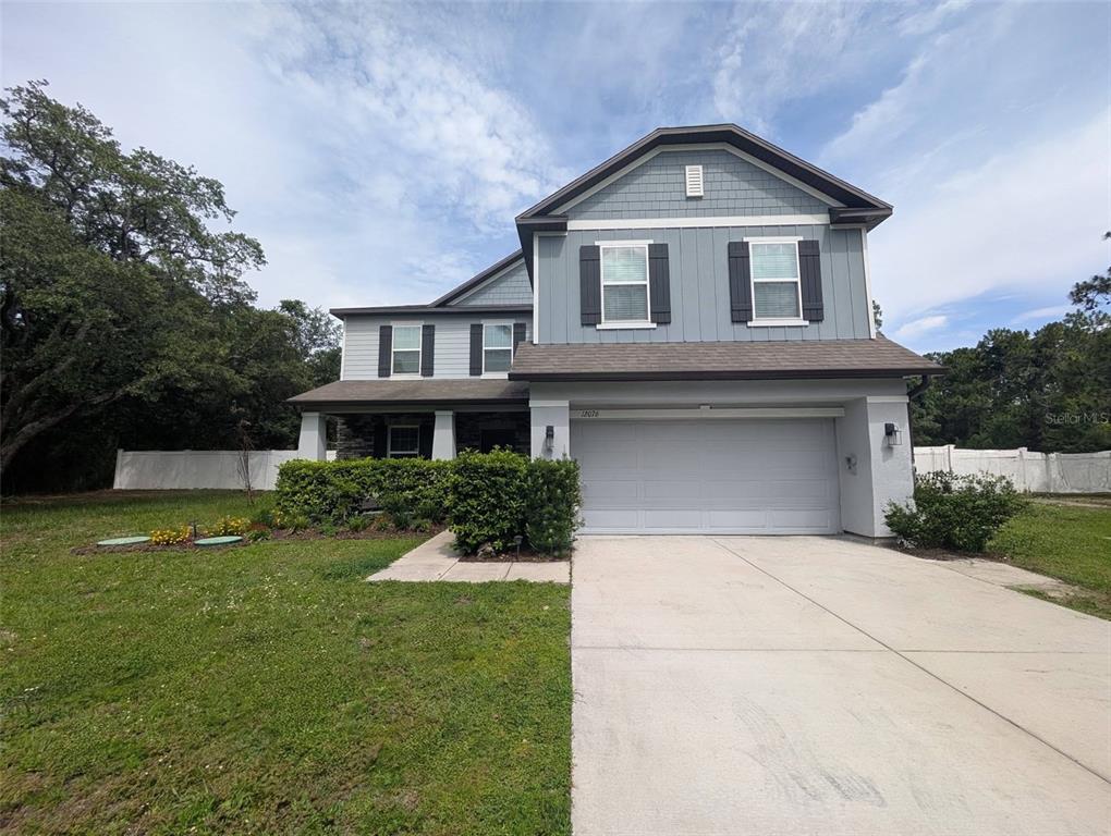 A two-story house with blue siding, a two-car garage, and a front lawn — 12076 MARVELWOOD ROAD, WEEKI WACHEE, FL