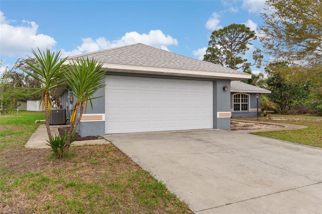 A gray house with a two-car garage, a concrete driveway, and a small palm tree — 4716 BOABADILLA AVENUE, SEBRING, FL