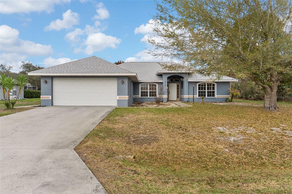 A single-story blue house with a two-car garage, arched entryway, and a large front yard — 4716 BOABADILLA AVENUE, SEBRING, FL