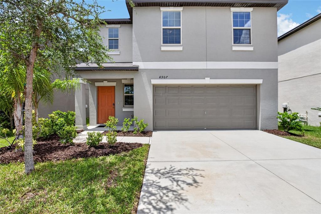 A two-story house with a gray exterior, a two-car garage, and an orange front door — 4907 WILD SENNA BOULEVARD, TAMPA, FL