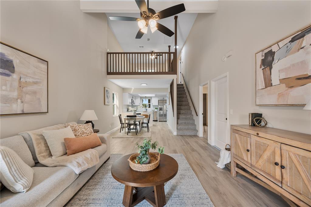 A living room with a vaulted ceiling, loft balcony, and open kitchen in the background — 265 LAKE THOMAS DRIVE, WINTER HAVEN, FL