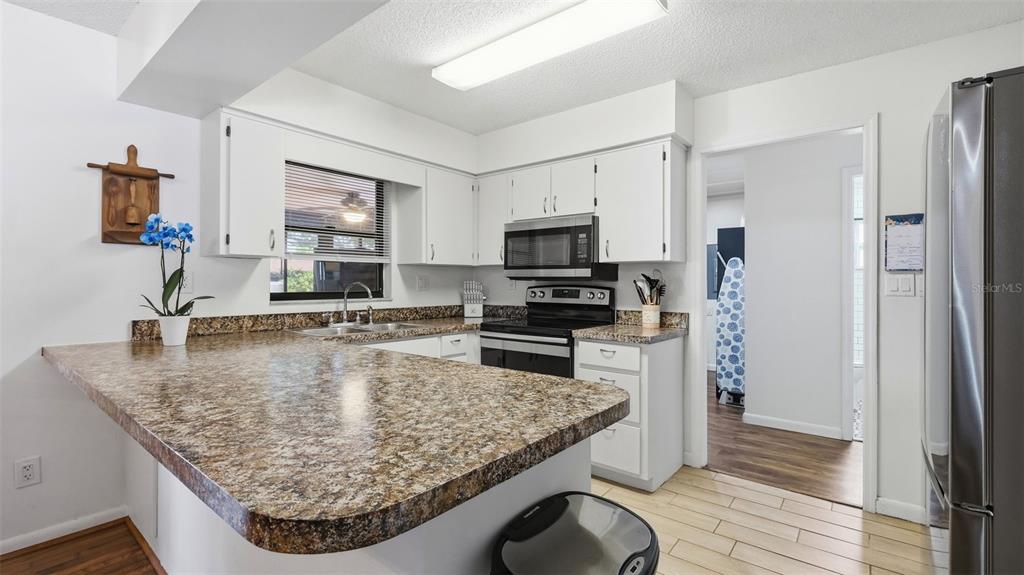 A kitchen features white cabinets, speckled laminate countertops, stainless steel appliances, and tile flooring — 7020 ASHMONT AVENUE, BROOKSVILLE, FL