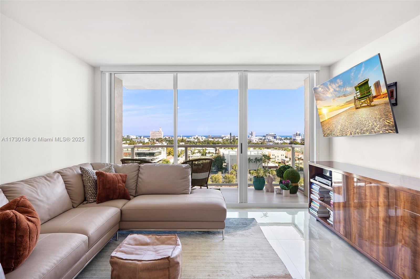 A living room features a beige sectional sofa, a wooden media console, and a balcony view — 650 West Ave # 1004, Miami Beach FL 33139, MIAMI BEACH, FL