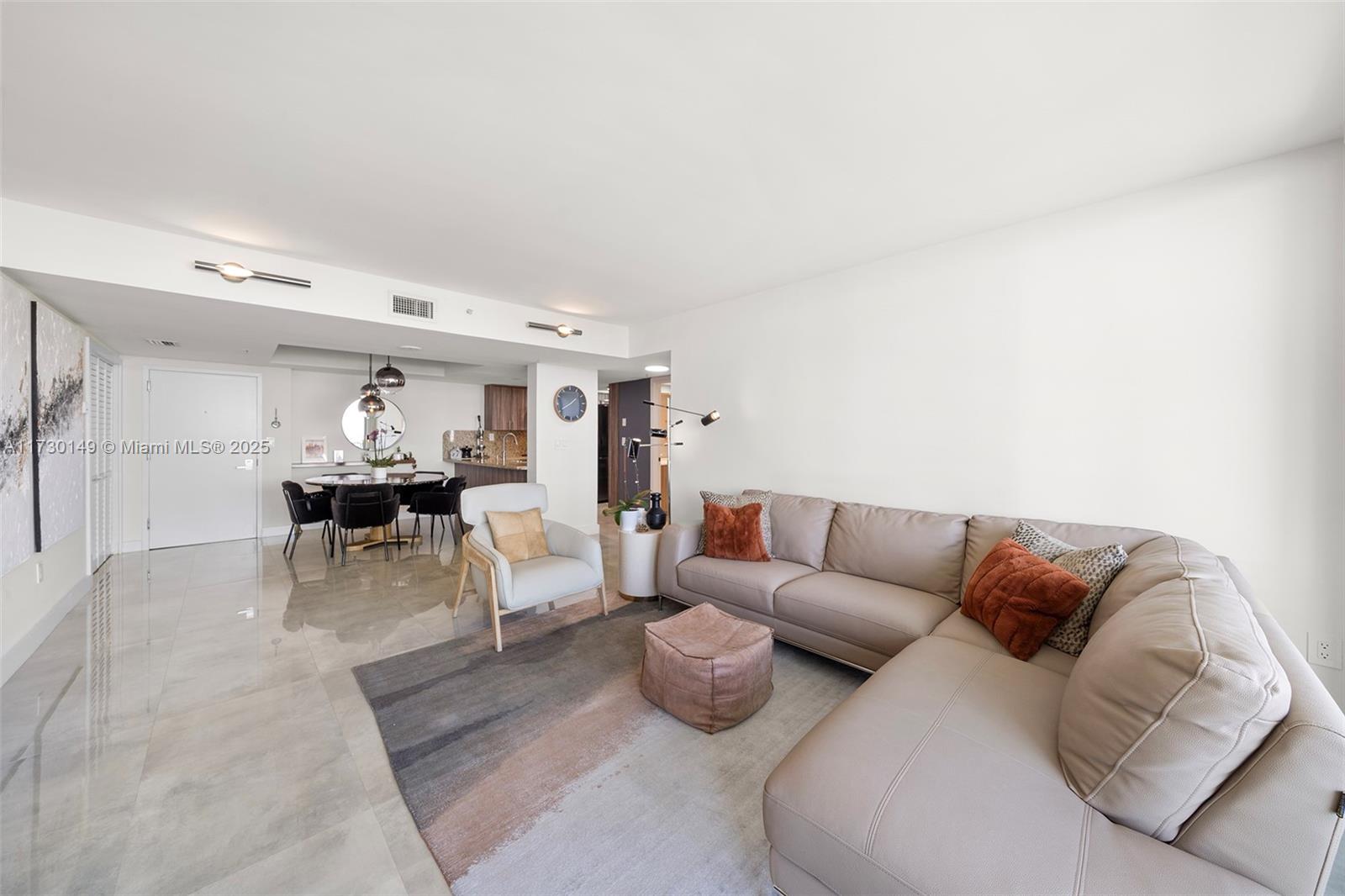 A modern living room features a beige sectional sofa, a patterned rug, and an adjacent dining area — 650 West Ave # 1004, Miami Beach FL 33139, MIAMI BEACH, FL