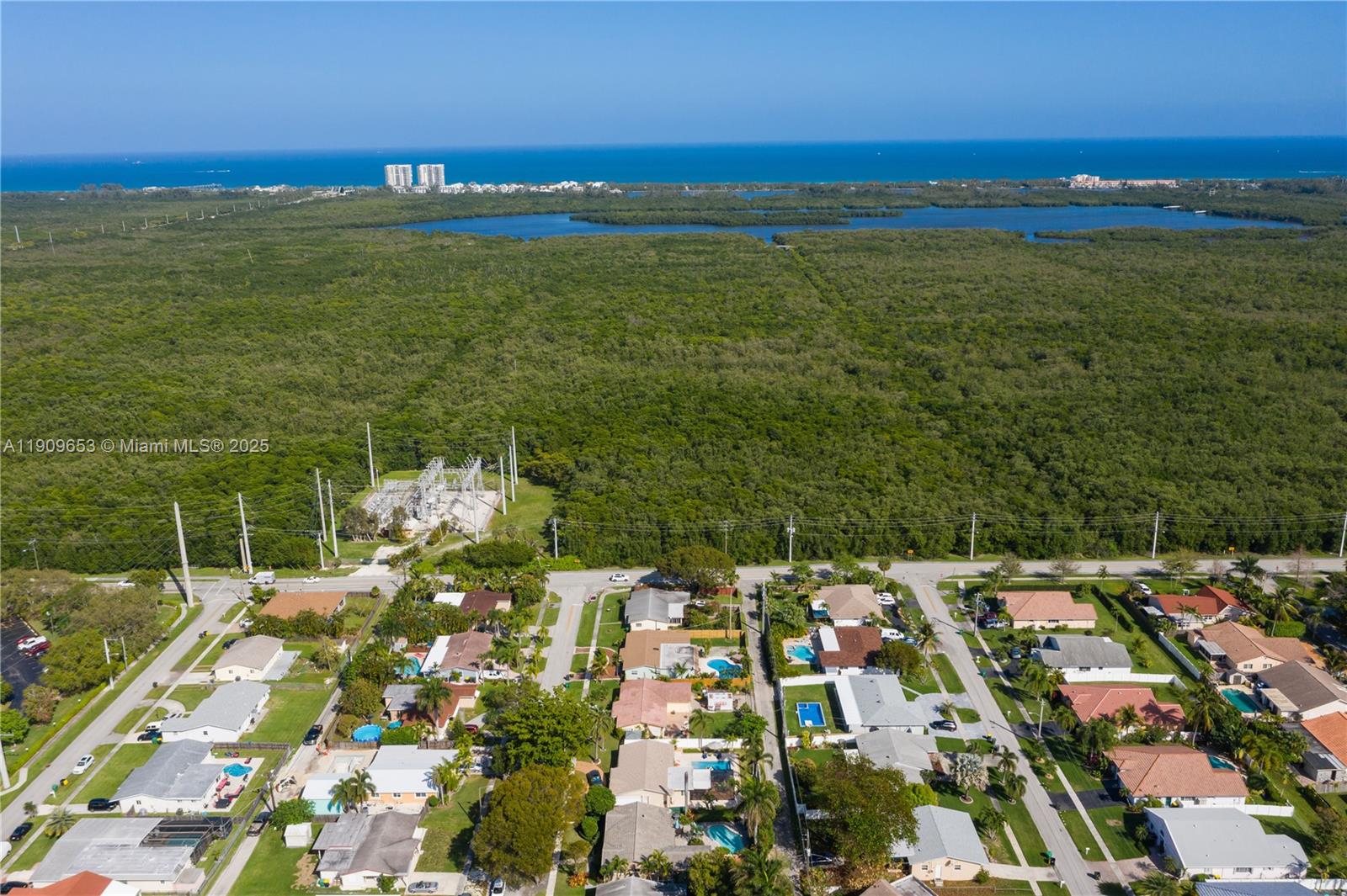 An aerial view shows a residential neighborhood bordering a large forest and a power substation — 418 SE 3rd Ter # 0, Dania Beach FL 33004, DANIA BEACH, FL