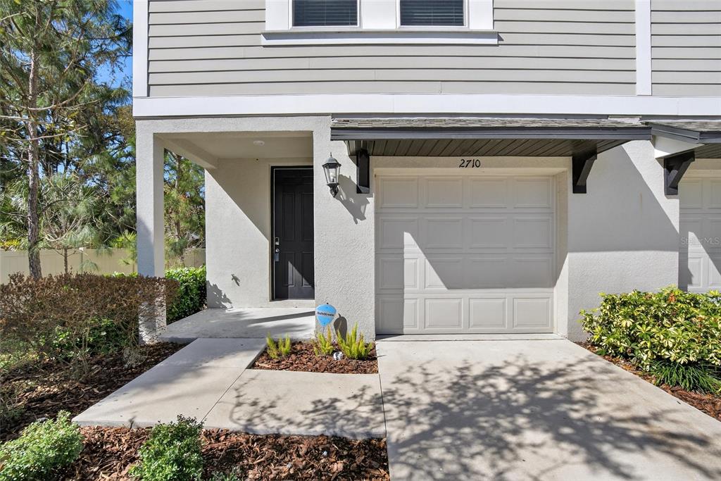 The exterior of a two-story townhouse features a garage, a front door, and landscaping — 2710 SCARLET BAY PLACE, BRANDON, FL