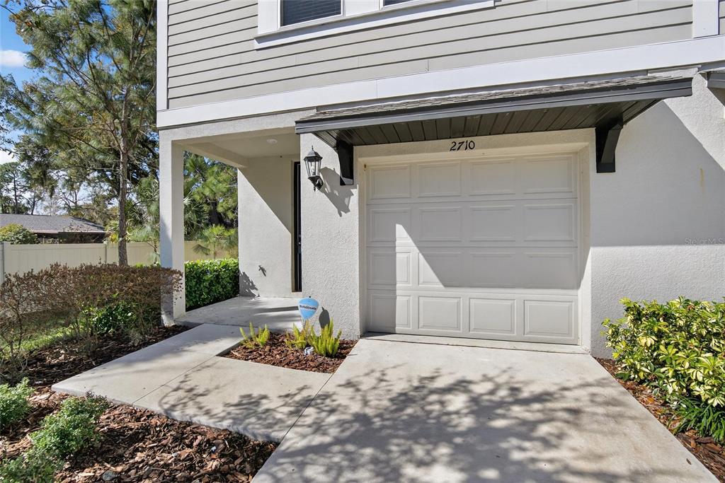 A single-car garage with a covered entryway and concrete driveway at a residential home — 2710 SCARLET BAY PLACE, BRANDON, FL