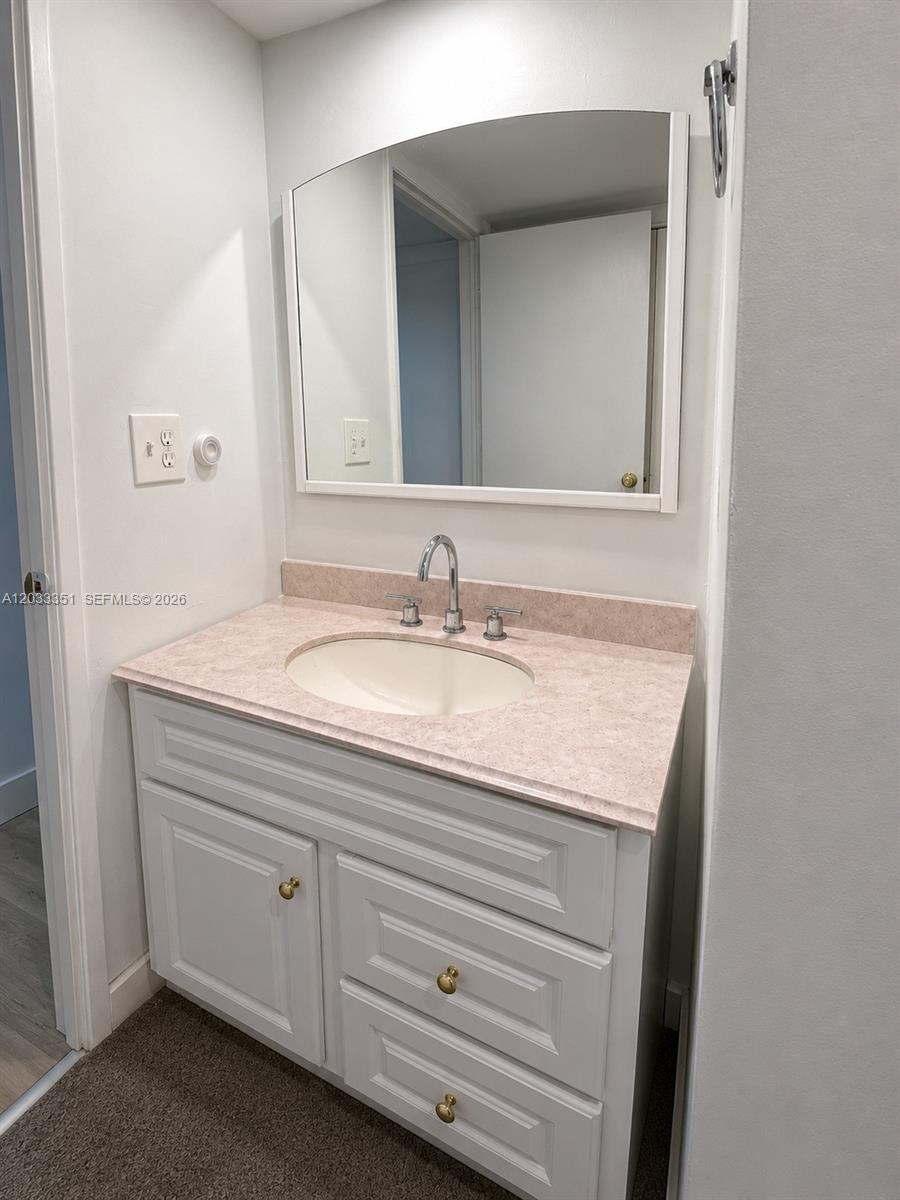 A bathroom vanity features a pink speckled countertop, white cabinetry, and a wall-mounted mirror — 301 Bonaventure Blvd # 7, Weston FL 33326, WESTON, FL