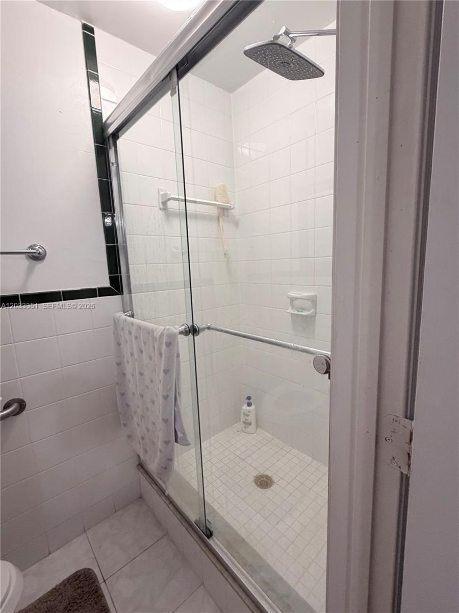 A tiled walk-in shower features a glass sliding door and a square rainfall showerhead — 301 Bonaventure Blvd # 7, Weston FL 33326, WESTON, FL