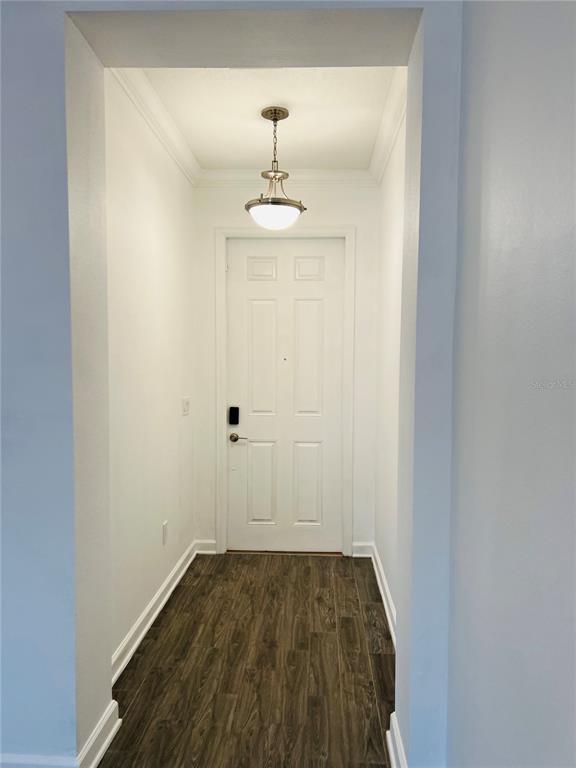 A white door with a smart lock stands at the end of a wood-floored entryway — 11258 WHISTLING PINE WAY, ORLANDO, FL