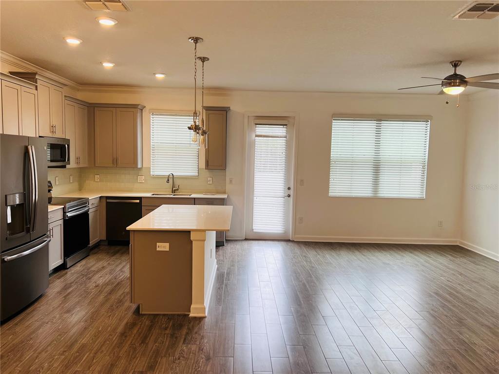 A kitchen with gray cabinets, a central island, and wood-look flooring in an open space — 11258 WHISTLING PINE WAY, ORLANDO, FL