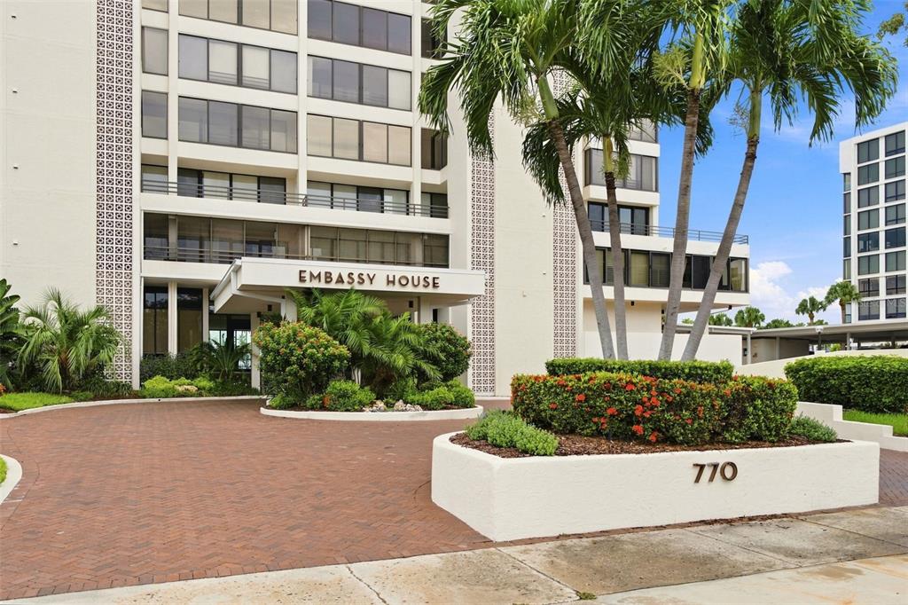 The exterior of a multi-story residential building features a brick driveway and palm trees — 770 S PALM AVENUE UNIT 1804, SARASOTA, FL