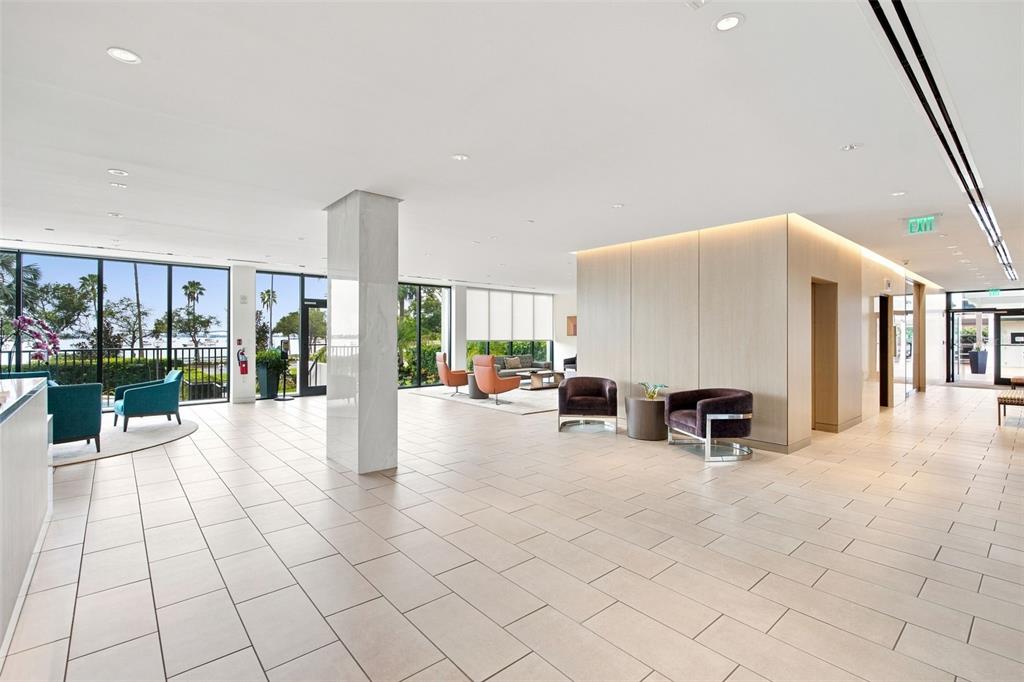 A modern lobby features light tile flooring, floor-to-ceiling windows, and various seating areas — 770 S PALM AVENUE UNIT 1804, SARASOTA, FL