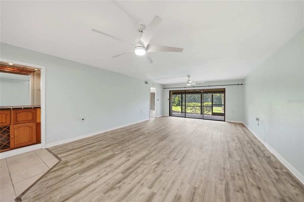 A spacious room with light wood-look flooring, two ceiling fans, and a sliding glass door — 601 SHREVE STREET UNIT 51A, PUNTA GORDA, FL