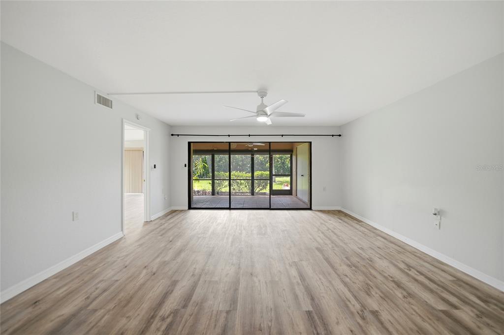 An open-concept living and dining area featuring light wood flooring, a ceiling fan, and furniture — 601 SHREVE STREET UNIT 51A, PUNTA GORDA, FL