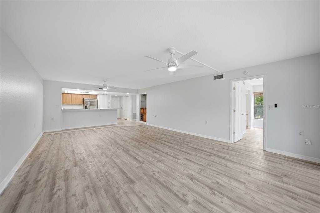 A spacious living room features light wood-look flooring, a ceiling fan, and sliding glass doors — 601 SHREVE STREET UNIT 51A, PUNTA GORDA, FL