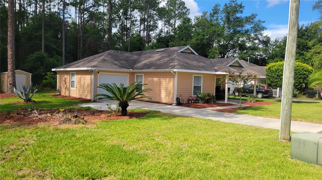 A single-story house with tan siding, a shingled roof, a garage, and a front lawn — 1517 NE 40TH PLACE, GAINESVILLE, FL