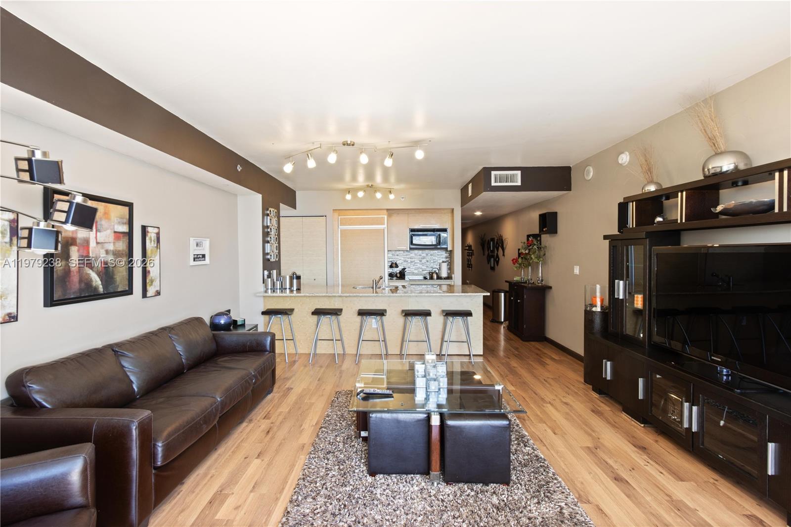 A living room features a brown leather sofa, a glass coffee table, and an open kitchen — 1830 S Ocean Dr # 2105, Hallandale Beach FL 33009, HALLANDALE BEACH, FL