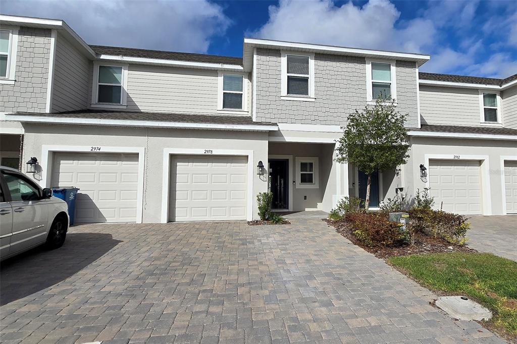 A two-story townhouse exterior features a paved driveway, two garage doors, and gray siding — 2978 CANARY AVENUE, DAVENPORT, FL