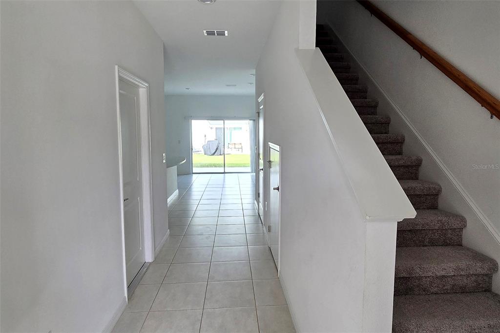 A tiled entryway leads to a living area with sliding glass doors and a staircase — 2978 CANARY AVENUE, DAVENPORT, FL