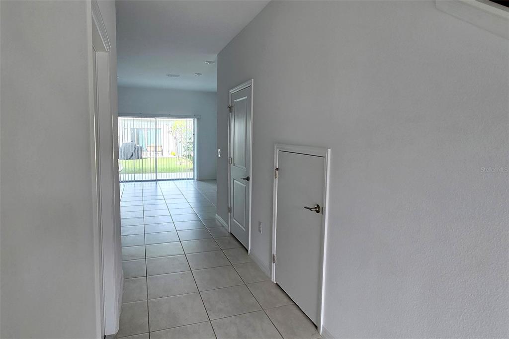 A hallway with tile flooring leads to a living area with sliding glass doors — 2978 CANARY AVENUE, DAVENPORT, FL