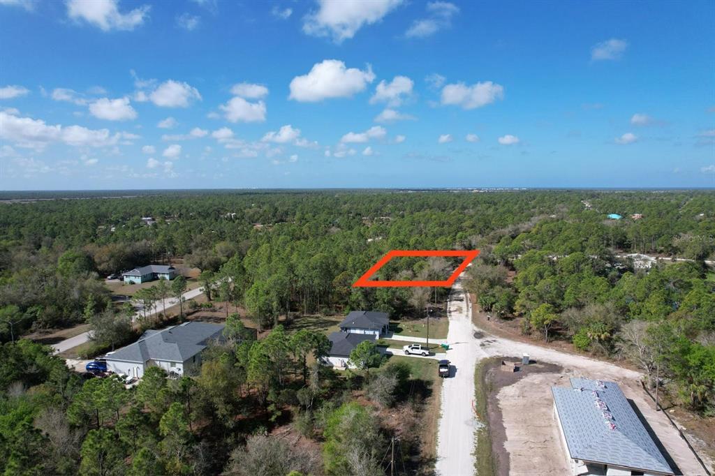 An aerial view shows a vacant, wooded residential lot outlined in red along a dirt road — 28101 LAURELWOOD DRIVE, PUNTA GORDA, FL