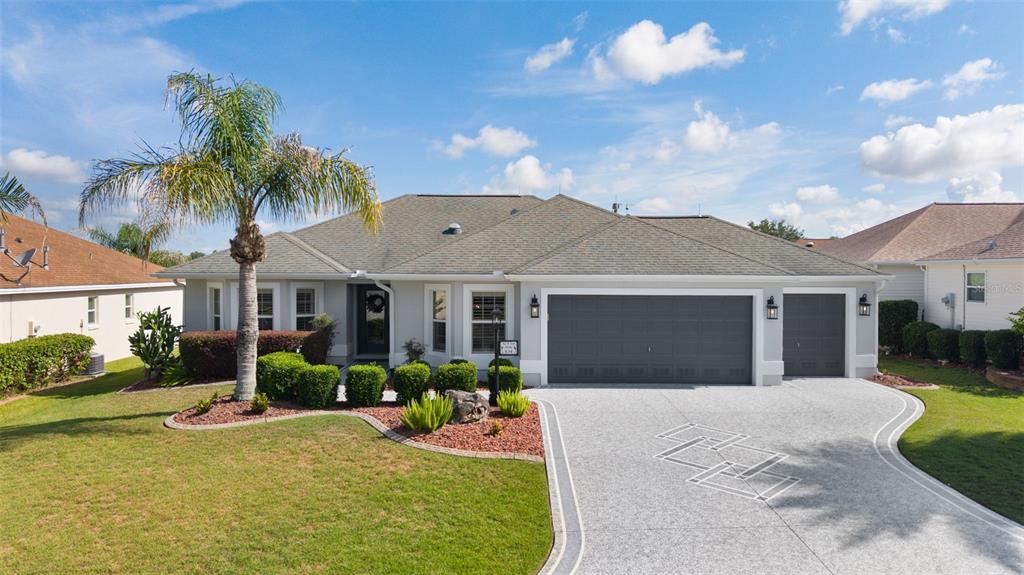 A single-story house with a gray garage, a palm tree, and a landscaped front yard — 634 ALLENWOOD LOOP, THE VILLAGES, FL